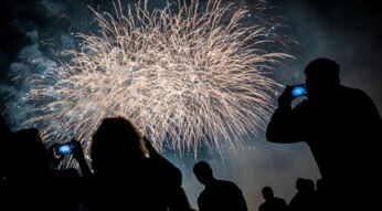 Silhouetten von Menschen, die ein Feuerwerk mit ihren Smartphones filmen