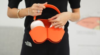 Junge Frau packt ihre AirPods Max in eine passende Hülle in elegantem Orange.
