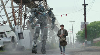 Noah (Anthony Ramos) und Transformer Mirage laufen nebeneinander eine Straße entlang im Film Transformers: Aufstieg der Bestien