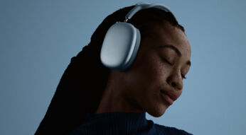 Ein junge Frau trägt AirPods Max 2 und hält dabei die Augen geschlossen.