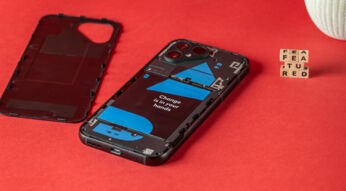 Das schwarze Fairphone 5 liegt mit abgetrennter Rückseite auf einem roten Untergrund, im Hintergrund ergeben Buchstabenwürfel den Schriftzug featured