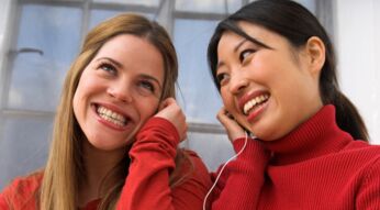 Zwei Frauen, die sich kabelgebundene Kopfhörer teilen.