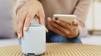 Nahaufnahme von einer Hand, die einen Lautsprecher mit einem Smartphone verbinden will.