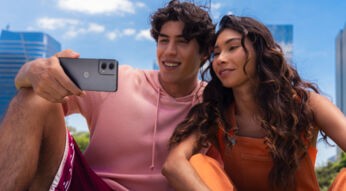 Ein junger Mann und eine junge Frau gucken unter freiem Himmel zusammen auf das Display des Handys Moto G24