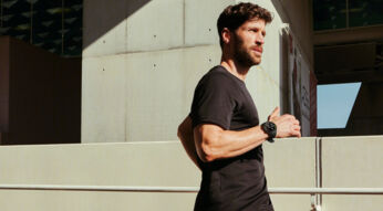 Mann läuft in der Stadt der Sonne entgegen mit OnePlus Watch 2 am Handgelenk