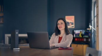 Frau sitzt mit Laptop neben Kabel Router
