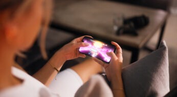 Eine Frau hält ein Handy in der Hand und spielt darauf ein Rennspiel.