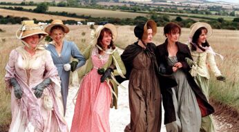 Netflix bringt eine Stolz und Vorurteil-Serie heraus. Auf dem Bild aus dem Stolz und Vorurteil-Film von 2005 sind sechs Frauen in historischen Kleidern auf einem Feldweg zu sehen. Zweite von rechts ist Elizabeth Bennet, gespielt von Keira Knightley, die in einem grauen Kleid und schwarzem Umhang lächelnd mit ihren Schwestern durch die Landschaft spaziert. Die Frauen wirken fröhlich und verbunden, was ihre enge Beziehung untereinander und die Heiterkeit der Szene widerspiegelt.