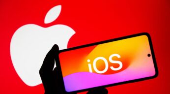 Das Logo von iOS ist auf einem iPhone abgebildet, das von einer menschlichen Hand hochgehalten wird.