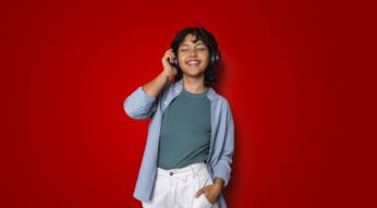 Auf dem Artikel-Bild zu Songs aus der Vodafone Werbung steht eine Frau mit geschlossenen Augen vor rotem Hintergrund, trägt schwarze Kopfhörer und hört Musik.