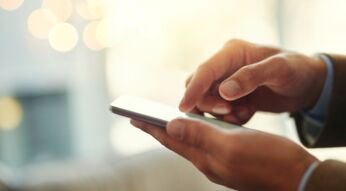 Mann tippt mit seiner Hand auf das Display eines Smartphones