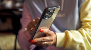 Frau zeigt mit ihrer Hand auf etwas auf dem iPhone.