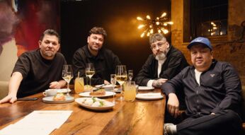 In dieser Szene aus Kitchen Impossible Staffel 10 sitzen Tim Mälzer, Marteria, Sido und The Duc Ngo gemeinsam an einem festlich gedeckten Tisch.