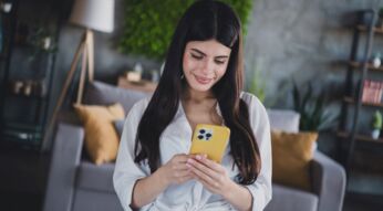 Junge Frau schaut auf ein iPhone mit gelber Hülle.