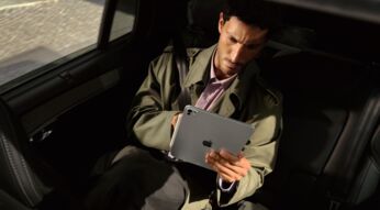 Mann sitzt im Auto und schaut auf das iPad Pro in seinen Händen.