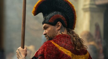 Auf dem Bild in dem Artikel zum „Chief of War“-Ende erklärt ist ein Mann mit rotem und gelben Umhang und aufwendigem Kopfschmuck zu sehen. Er hält einen Speer und schaut ernst zur Seite.