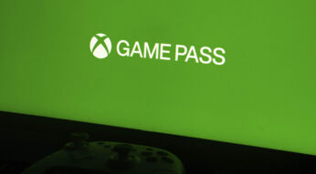 Ein Xbox-Controller liegt vor einem Monitor, der ein grünes Bild mit dem Game-Pass-Logo zeigt.