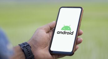 Ein Mann hält Smartphone hoch, auf dem das Android-Logo zu sehen ist