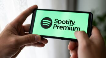 Das Spotify-Logo und der Text "Spotify Premium" sind auf einem Handy zu sehen, das jemand in der Hand hält.