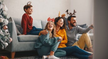Familie sitzt an Weihnachten gemeinsam vor dem Fernseher und schaut Weihnachtsfilme bei GigaTV