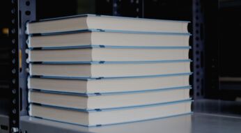 Bücher stehen gestapelt in einem Regal.