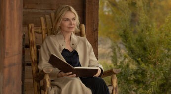 Michelle Pfeiffer als Stacy Clyburn in Staffel 1, Folge 4 der Paramount+-Serie "The Madison". Sie sitzt auf einer Veranda und hat ein Buch auf ihrem Schoß. Sie schaut aber nicht hinein, sondern in die Ferne.