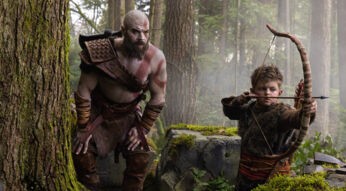 Auf dem Bild aus God of War sind Kratos und Atreus in einem dichten Wald zu sehen. Links steht Kratos, ein großer muskulöser Krieger mit Glatze, roter Kriegsbemalung und Lederrüstung, der aufmerksam beobachtet. Rechts spannt Atreus konzentriert seinen Bogen mit eingelegtem Pfeil. Die Szene wirkt angespannt und lehrreich, während Kratos den jungen Jäger im Wald trainiert.