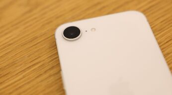 Das weiße iPhone 16e liegt in einem Apple Store auf einem Holztisch.