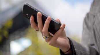 Frau hält schwarzes iPhone in der Hand.