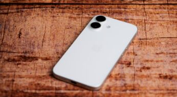 Das weiße iPhone 16 liegt auf einer Holzoberfläche.