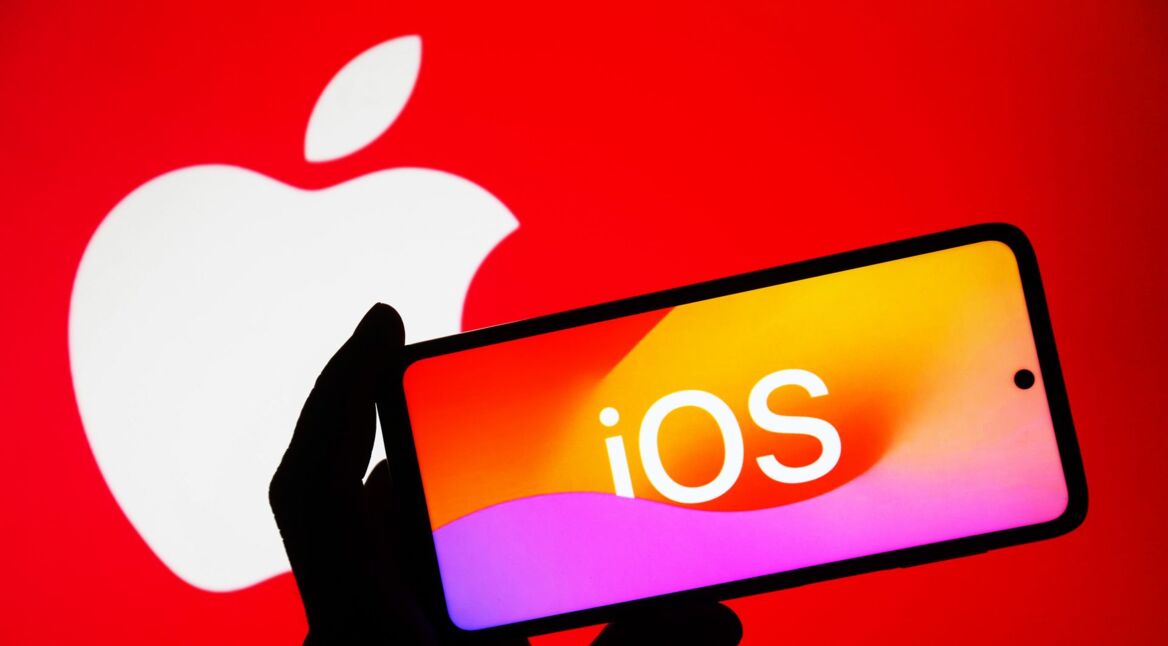 Das Logo von iOS ist auf einem iPhone abgebildet, das von einer menschlichen Hand hochgehalten wird.