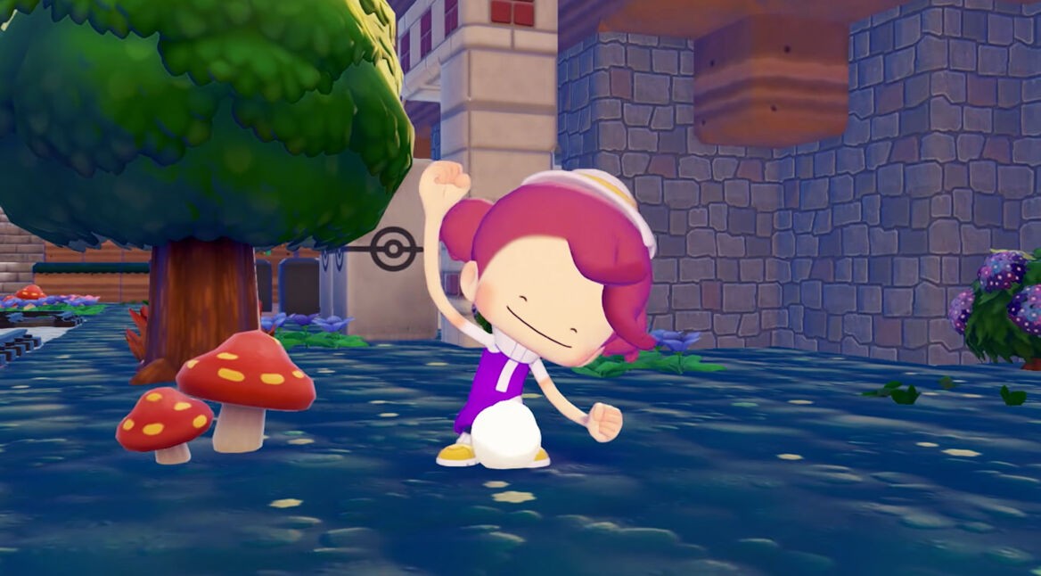 Eine Spielfigur tanzt fröhlich in der bunten Spielwelt von „Pokémon Pokopia“ neben einem Baum und roten Pilzen vor einer Steinmauer.