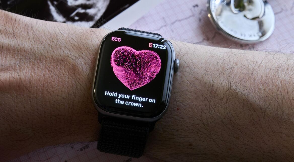 Die Apple Watch am Handgelenk zeigt die EKG-App an, die dazu auffordert, den Finger auf die digitale Krone zu legen.