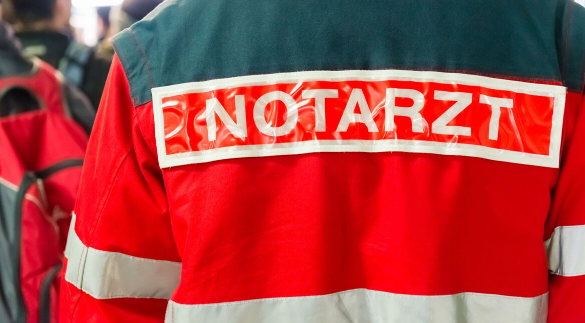 Ein Notarzt, dessen Jacke mit Aufschrift man von hinten sieht.