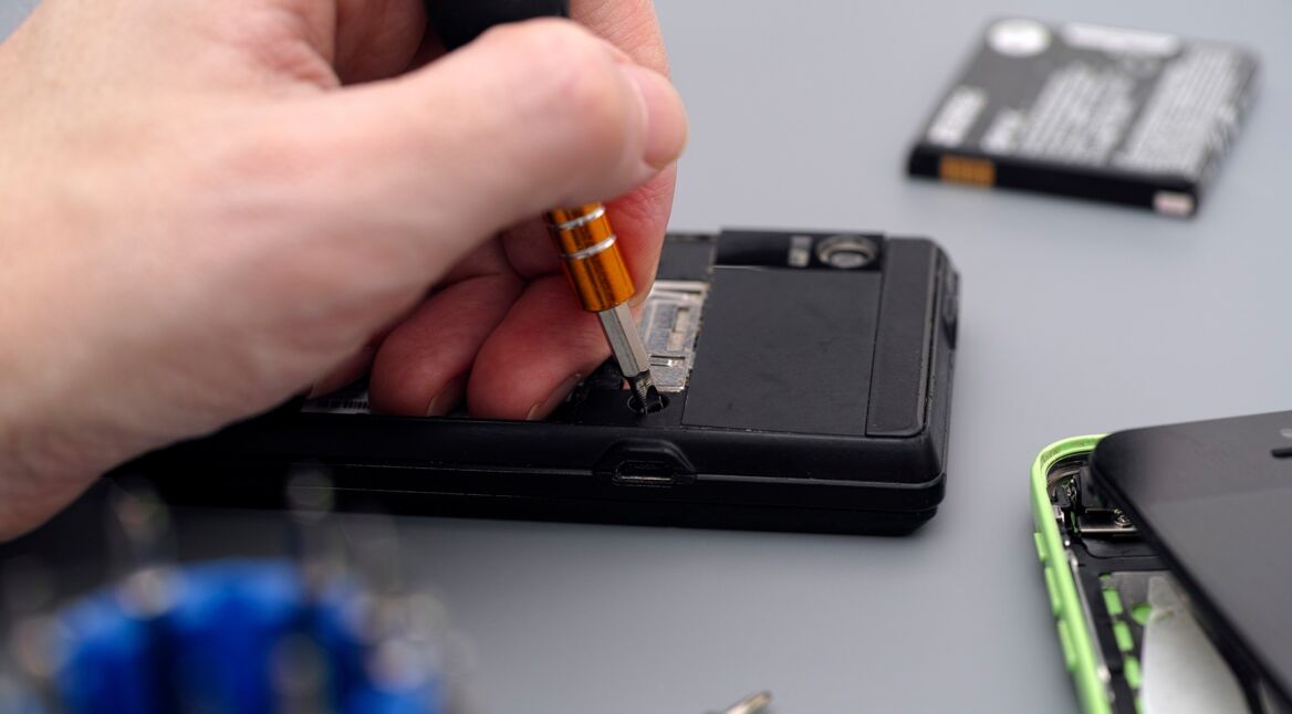 Man repairing cellphone with screwdriver