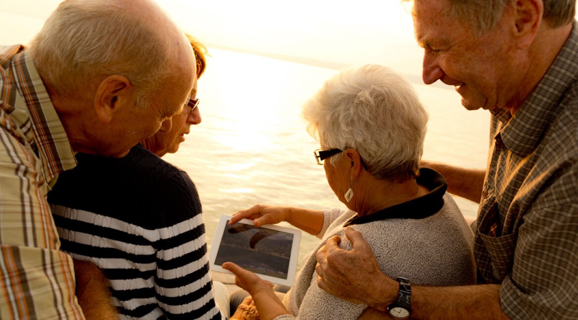 retirees with ipad at sunset