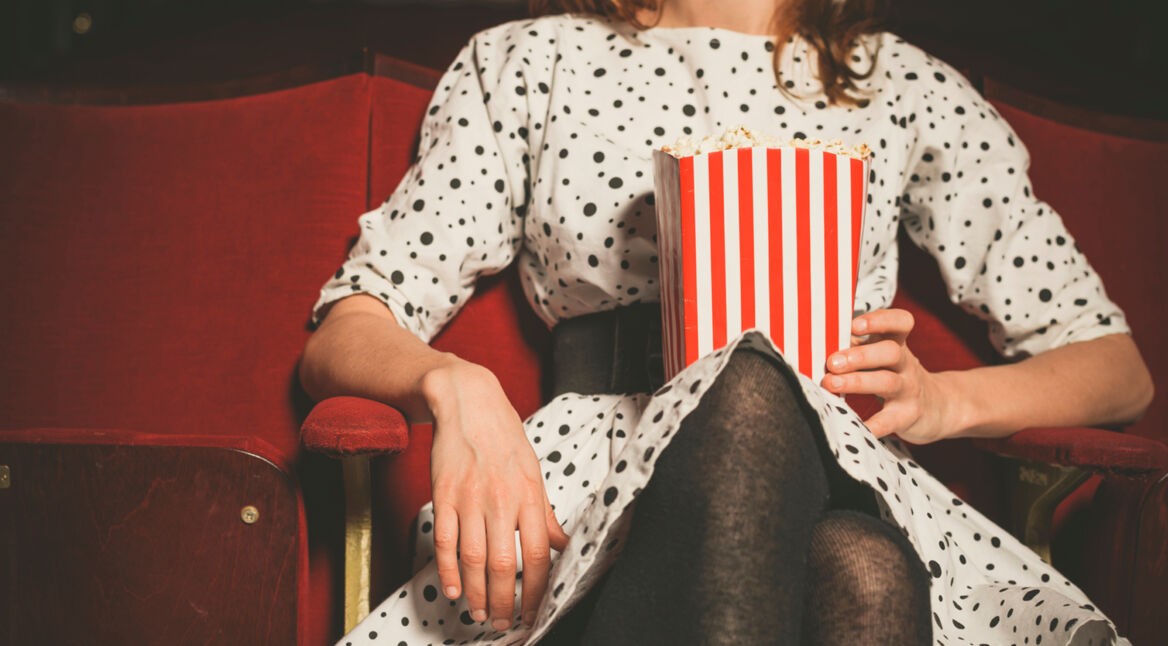 Young woman sitting in movie theater with popcorn