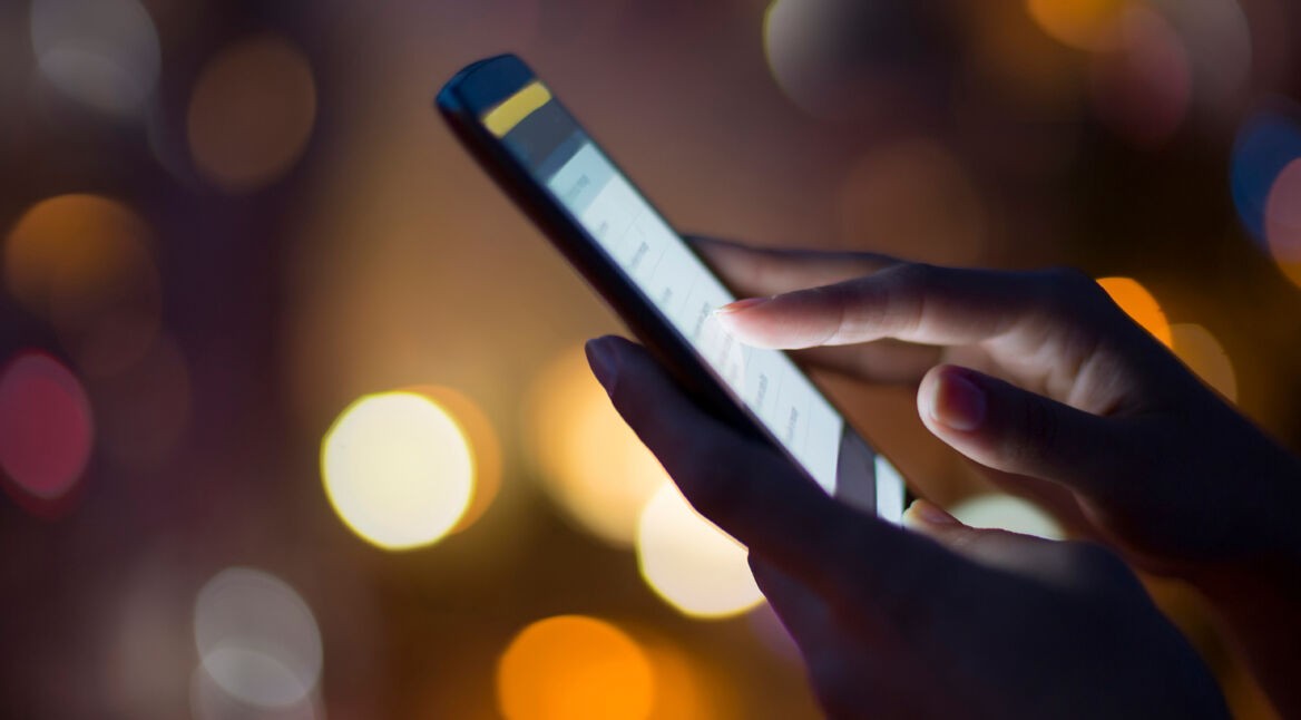 Woman using her mobile phone , city skyline night light  backgro