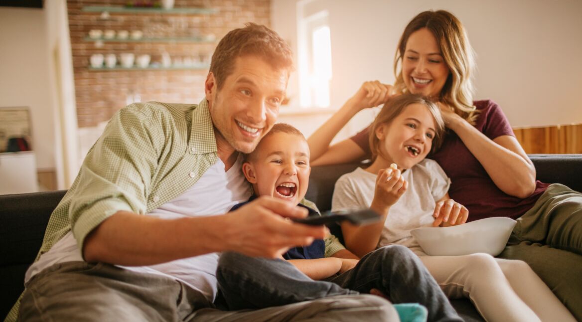Playful young family watching television