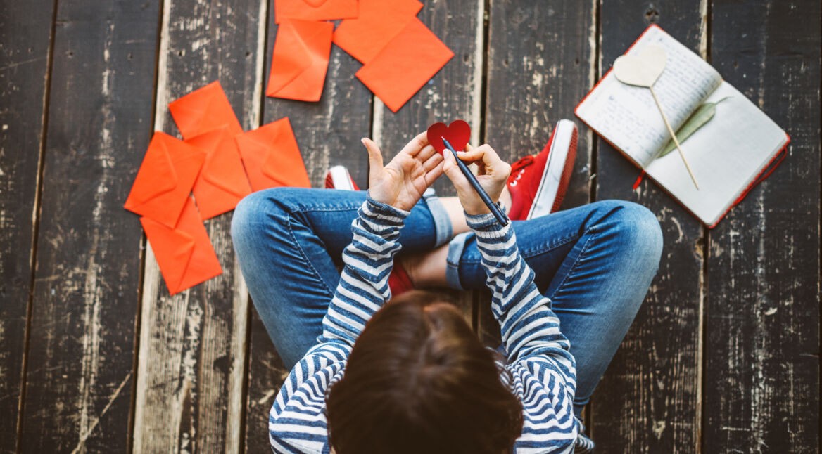 Young woman writing a valentine card - top view