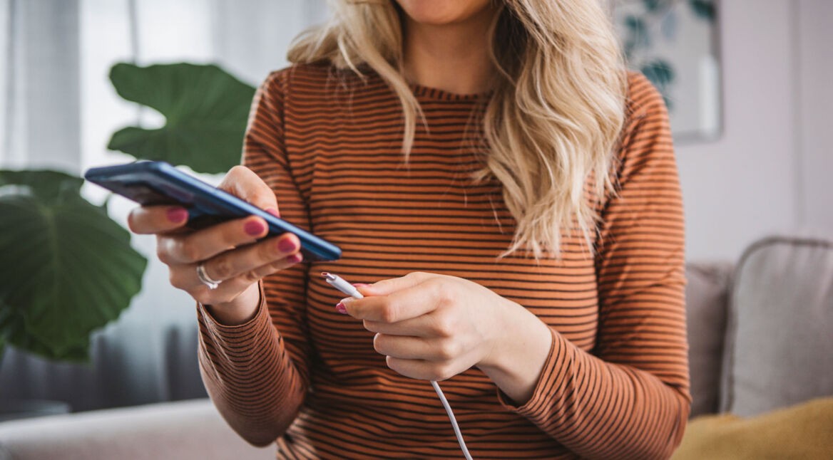 Eine Frau schließt ihr Smartphone zum Laden an