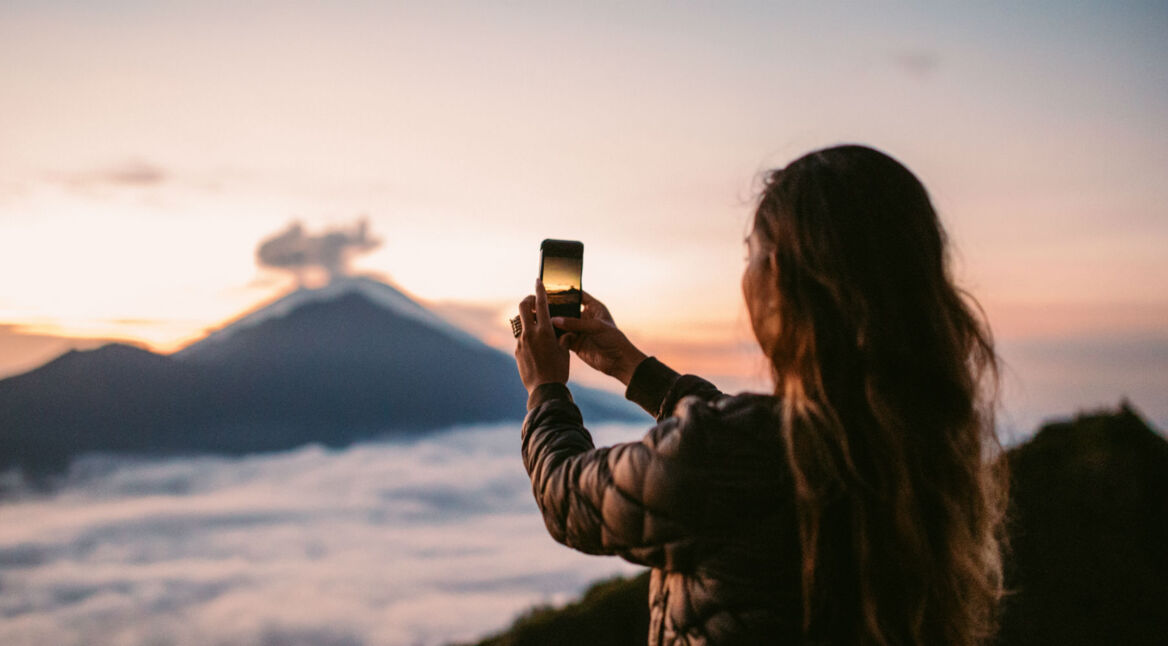 Junge Frau macht mit ihrem HTC-Smartphone Fotos vom Himmel.