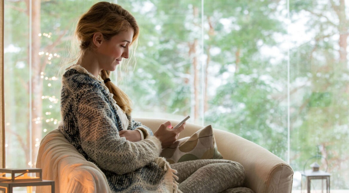 Junge Frau informiert sich am Smartphone über Samsung-Galaxy-S8-Tipps.