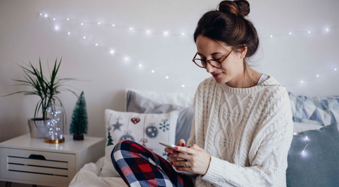Junge Frau informiert sich am Smartphone über iPhone-7-Tricks.
