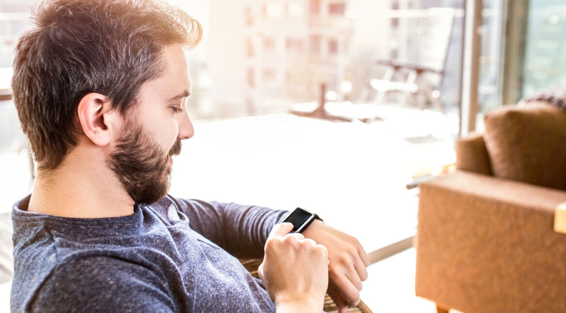 Mann sitzt auf dem Sofa und installiert Apps auf seiner Smartwatch