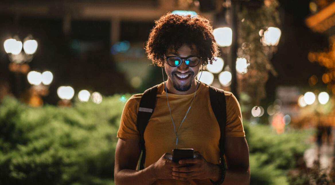 Junger Mann testet am Smartphone den Nachtmodus von WhatsApp.