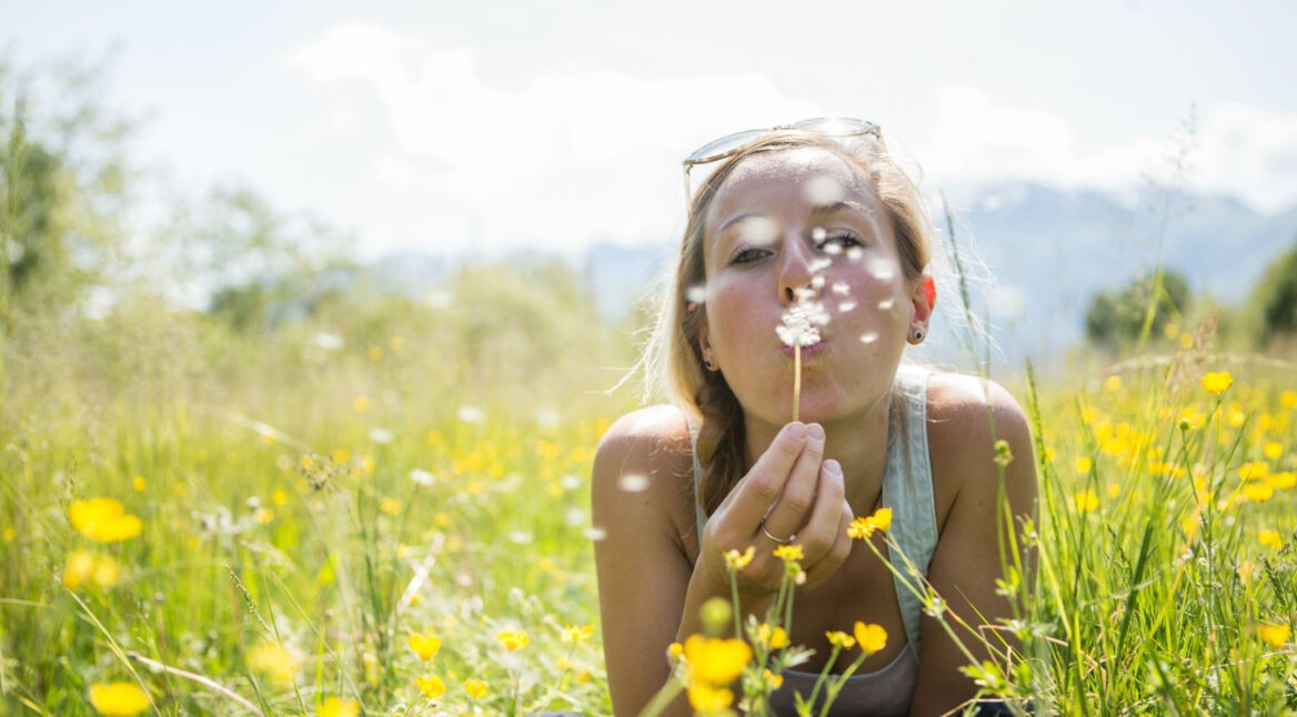 Frau auf Feld mit Pusteblume
