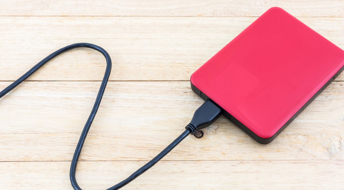 Rote externe Festplatte auf einem Tisch mit Kabel