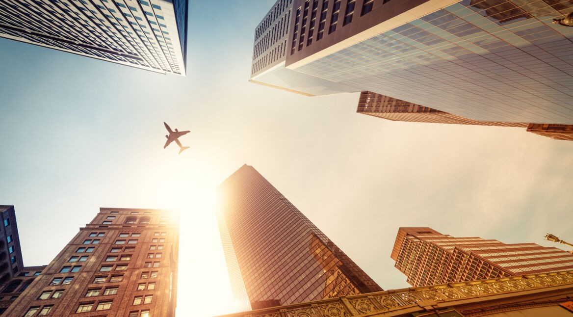 Flugzeug von unten zwischen Wolkenkratzern