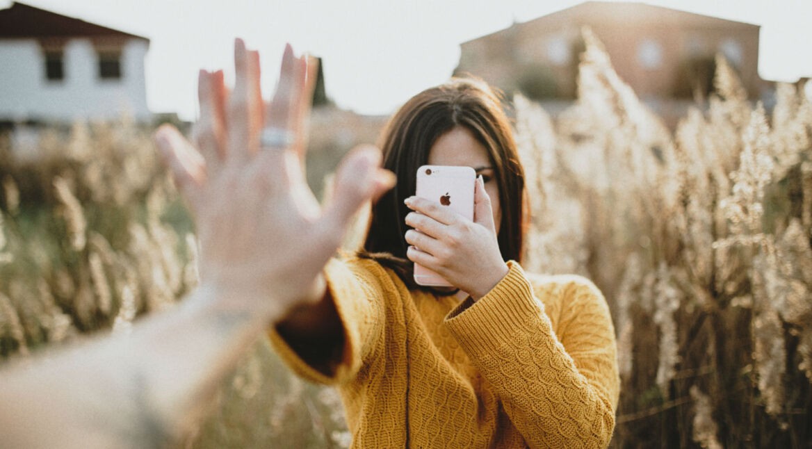 Frau schaut durch die iPhone-Kamera und macht High Five